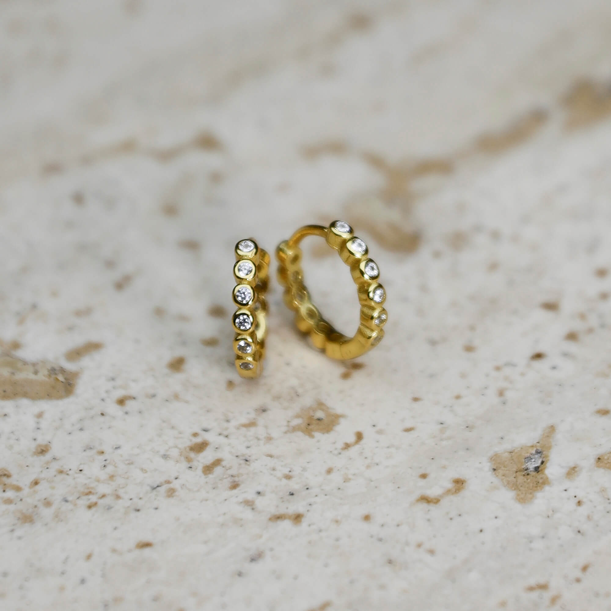 Close up gold-plated on sterling silver bezel-set stone huggie earrings, minimalist everyday jewellery, Solinu Jewellery.