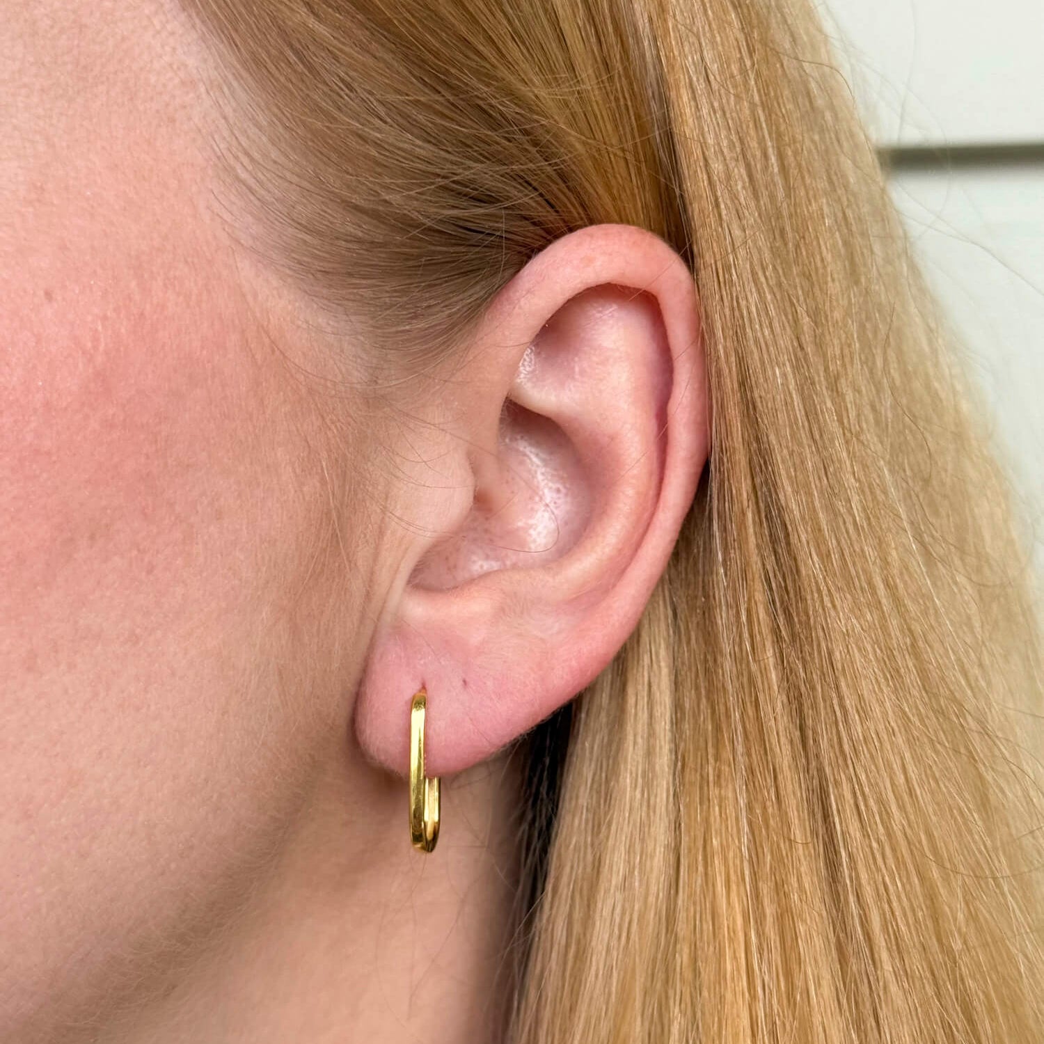 Model wearing gold-plated on sterling silver elongated hoop earrings with sleek minimalist silhouette, everyday jewellery essential. - Solinu Jewellery 