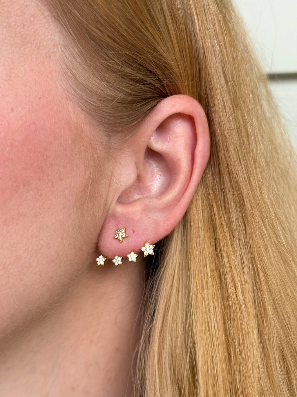 Model wearing gold-plated on sterling silver ear jacket climber earrings with star design, sparkling celestial shine. Solinu Jewellery 