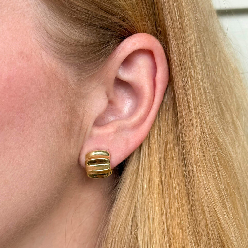 Model wearing gold-plated on sterling silver sculptural statement huggie earrings, polished contemporary design. - Solinu Jewellery 
