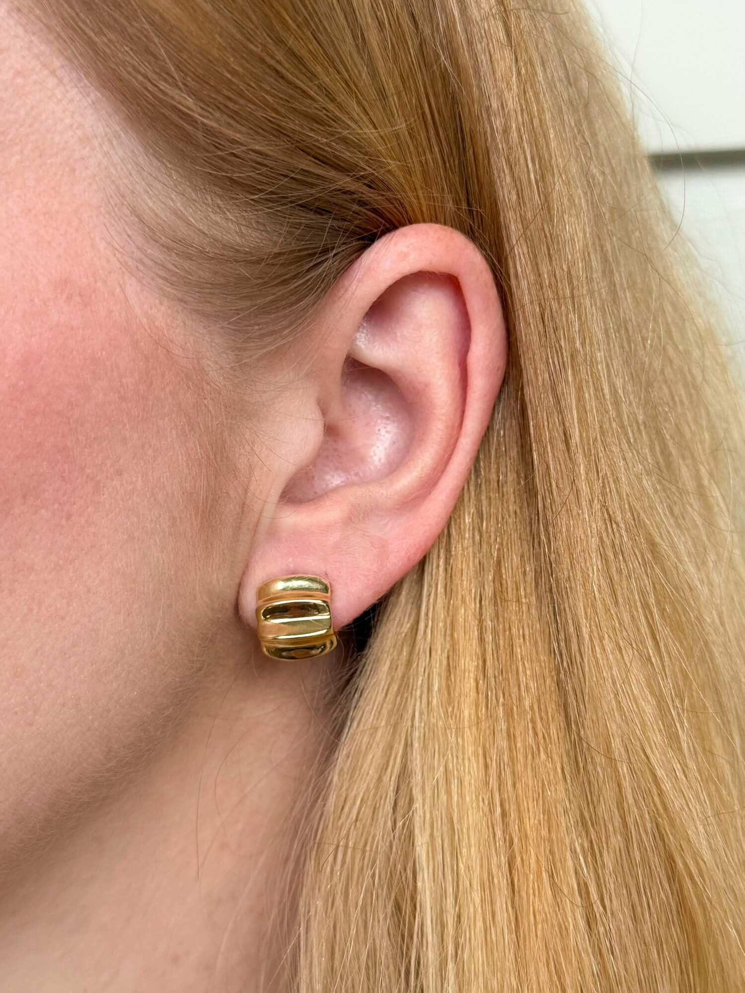 Model wearing gold-plated on sterling silver sculptural statement huggie earrings, polished contemporary design. - Solinu Jewellery 