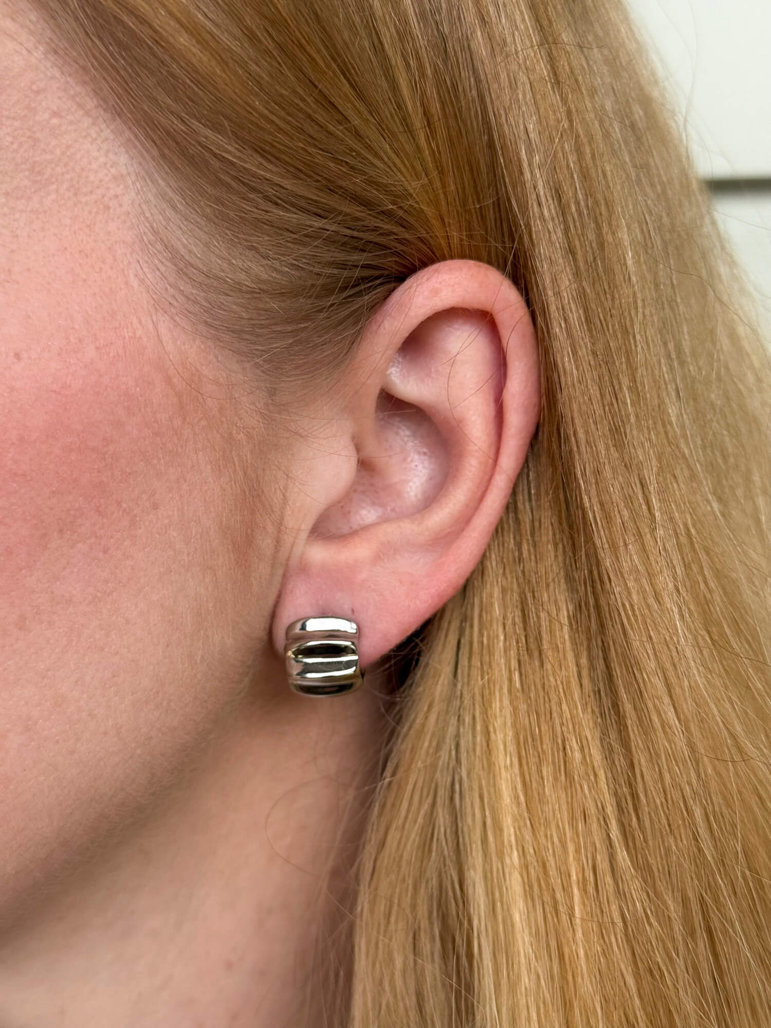 Model wearing sterling silver statement huggie earrings with bold sculptural design, modern elevated style. - Solinu Jewellery